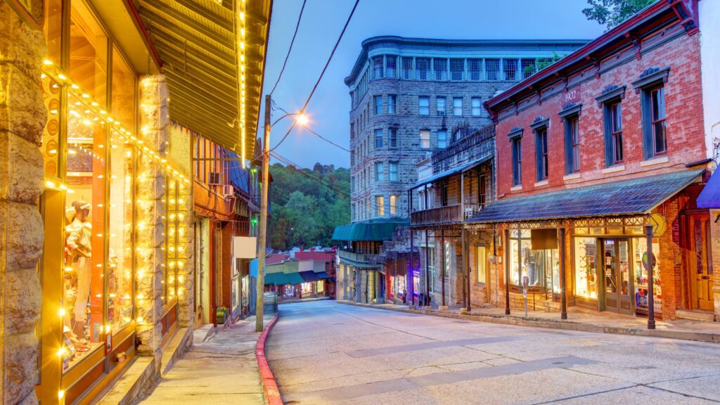 Downtown Eureka Springs at dusk, with historic buildings and winding streets.