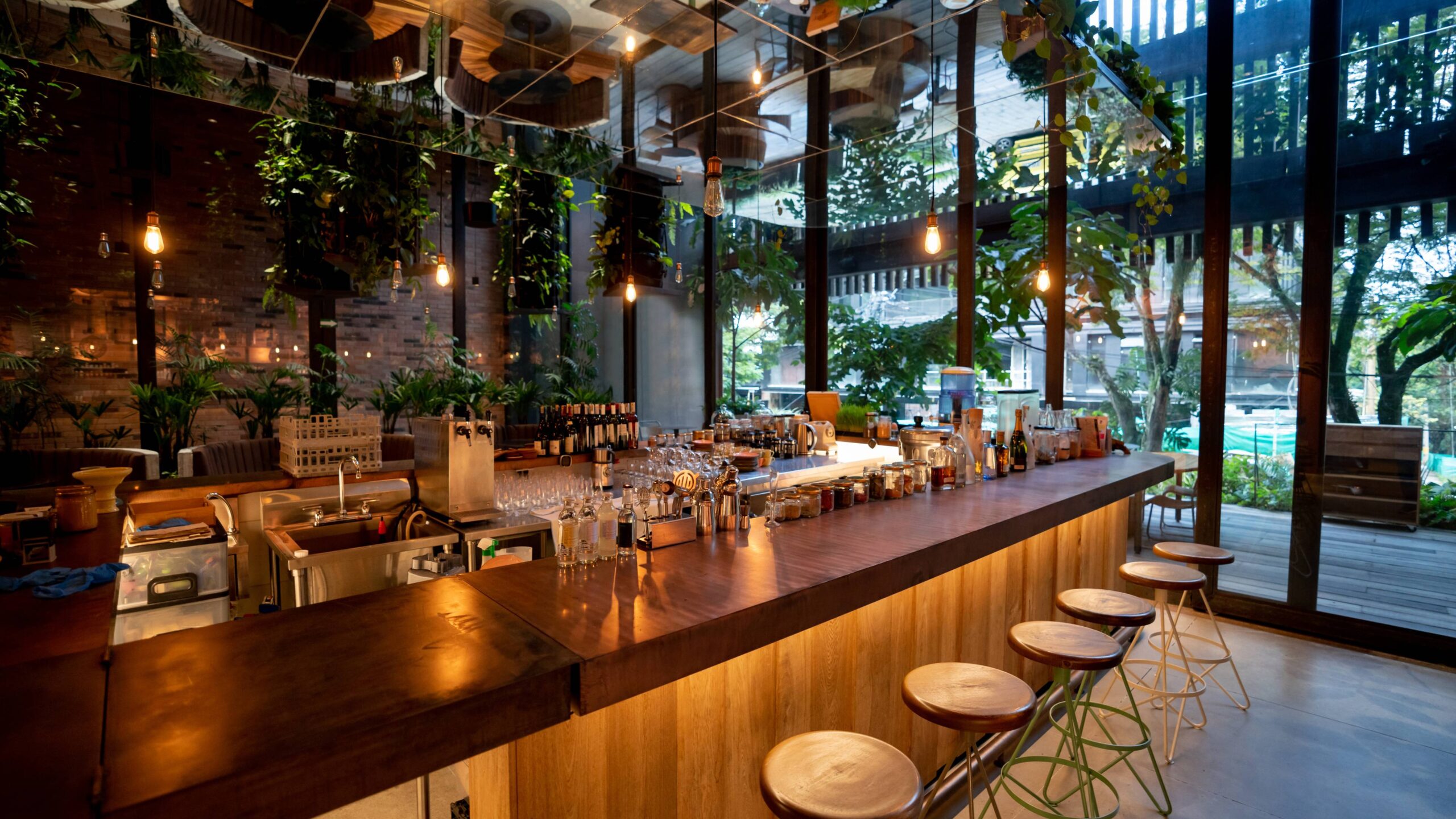 interior view of restaurant bar next to windows with greenery that look out onto a downtown street