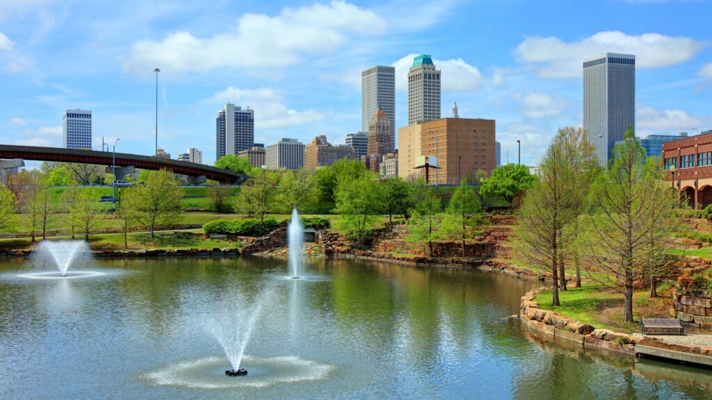 Downtown Tulsa skyline with riverfront park, fountains, and surrounding green space