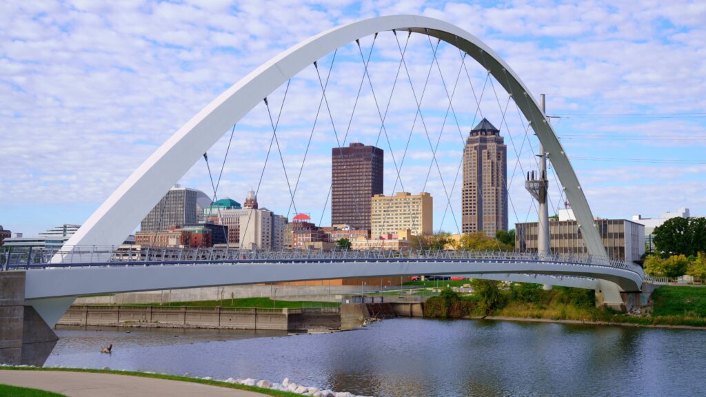 Des Moines skyline and riverfront, with the modern pedestrian bridge spanning the Des Moines River.
