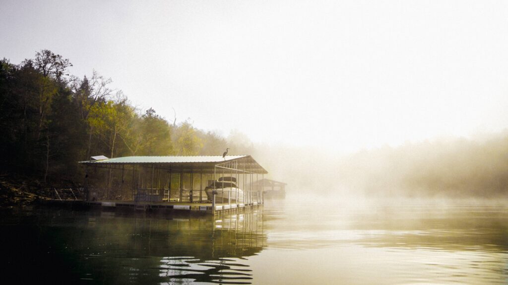 A quiet lakeside dock surrounded by trees and morning mist.